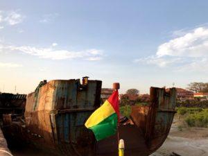 guinea bissau flag in front rotten ship keel