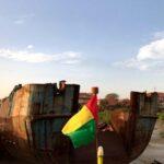 guinea bissau flag in front rotten ship keel