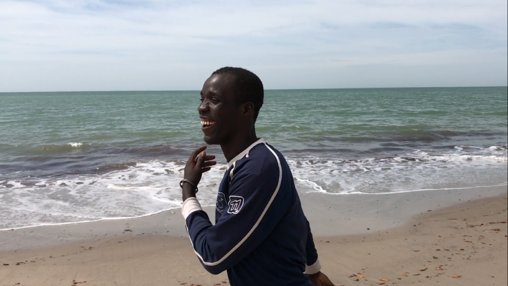 an african man in front of the atlantic ocean in palmarin, senegal