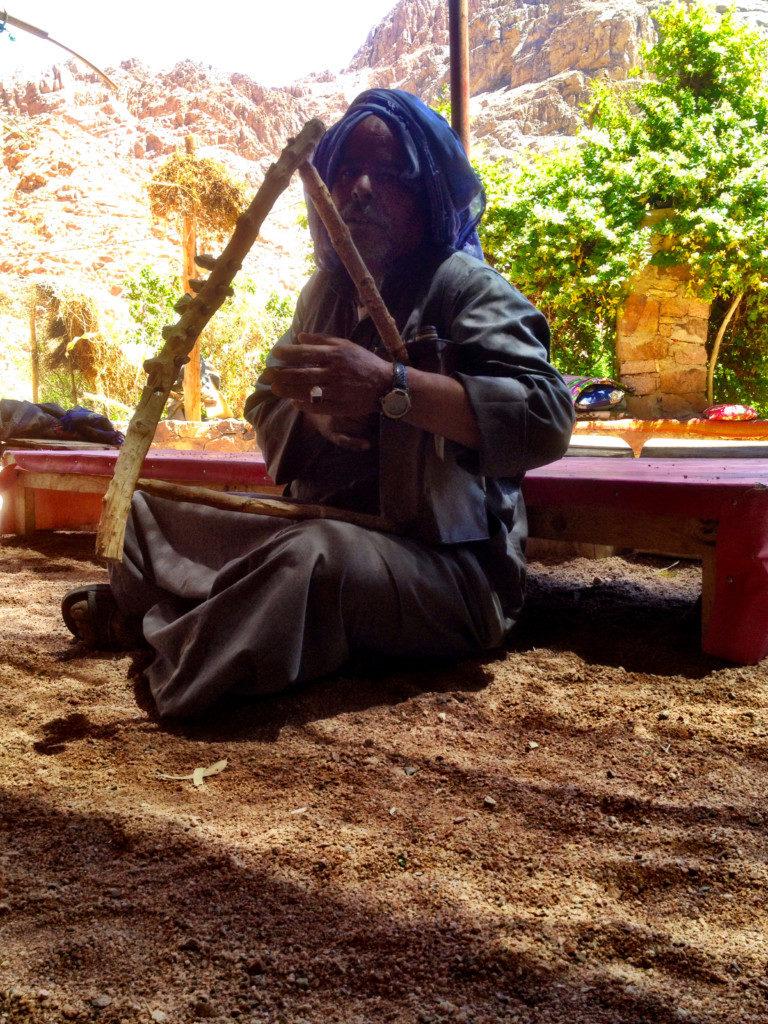 bedouing man playing self-made string instrument at him home in an oasis in mount sinai