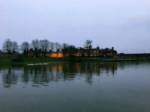 evening view of hampton court palace from the opposite bank on thames river