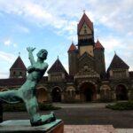 statue of kneeled man with his arm raised in front of fairy tale castle in leipzig, germany