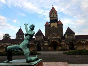 statue of kneeled man with his arm raised in front of fairy tale castle in leipzig, germany