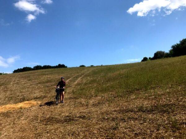 Pushing bicycle down a grassy hill near cattolica, italy