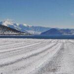 A snow covered field before Prespa Lake in Albania in the winter. Snowy mountains in the distance