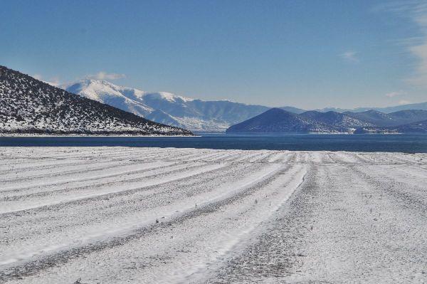 A snow covered field before Prespa Lake in Albania in the winter. Snowy mountains in the distance