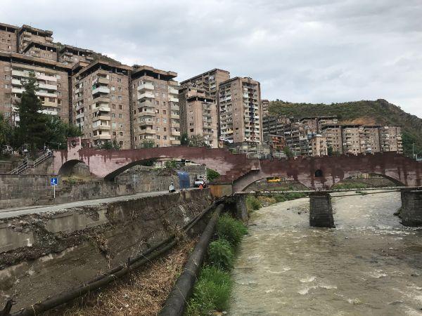 πολυκατοικίες και γέφυρα σε ορμητικό ποτάμι στην πόλη καπάν της αρμενίας