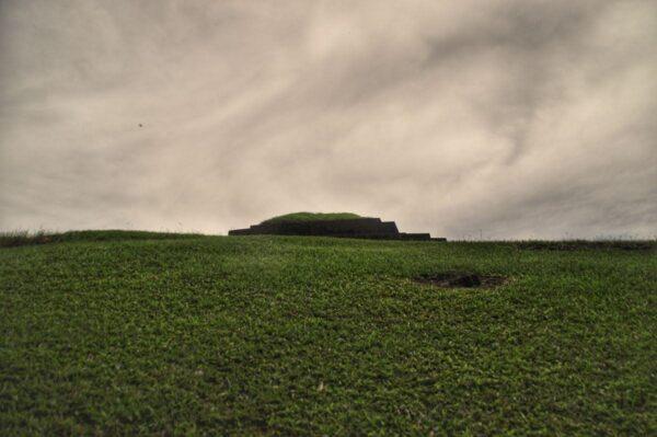 The grassed top of the pyramid protruding above a grassy mound