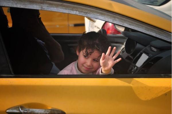 Little Iraqi girl greeting from car seat in Baghdad