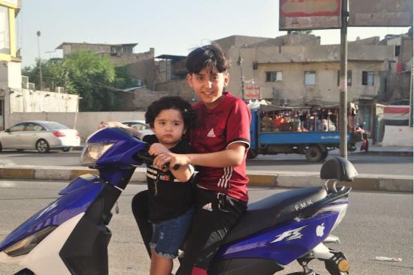 Young Iraqi boy driving a scooter in Baghdad