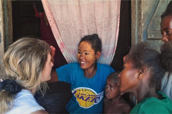 malagasy women in morondava applying traditional mask on european girl's face 