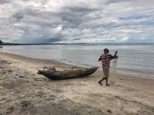Fisherman preparing net and pirogue mahambo beach madagascar