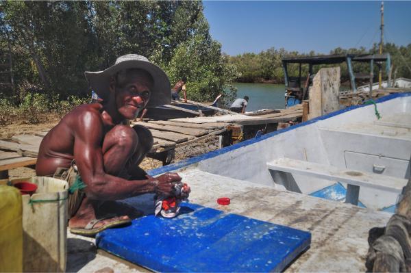old malagasy man washing a cloth on a boat