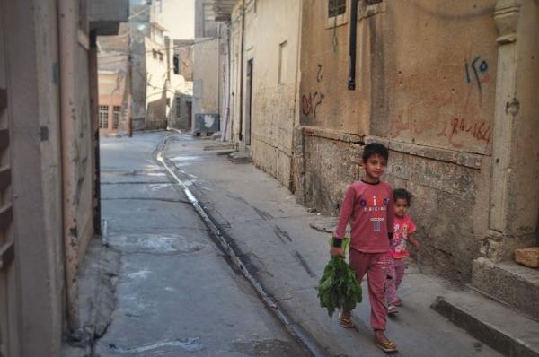 children walking through the backstreets of the old town of mosul in iraq