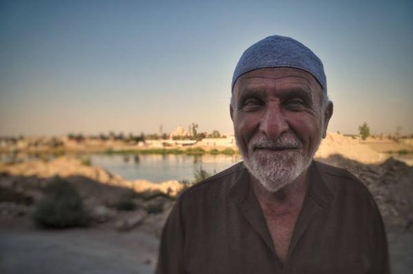 old iraqi man posing in front of tigris river and the great mosque of mosul
