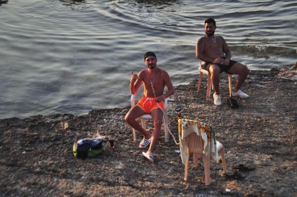 lebanese guys smoking shisha in swimwear by the shore