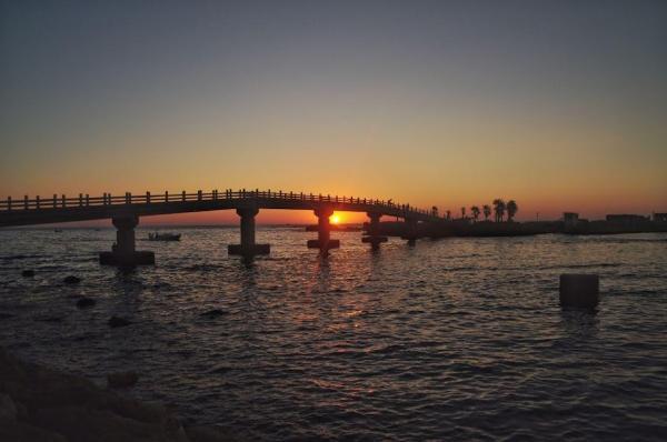 Sunset behind the bridge to Al Bakar Island of Mina coast, tripoli, lebanon