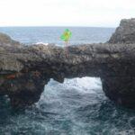 girl with green fabric standing atop pont naturel rock in mauritius