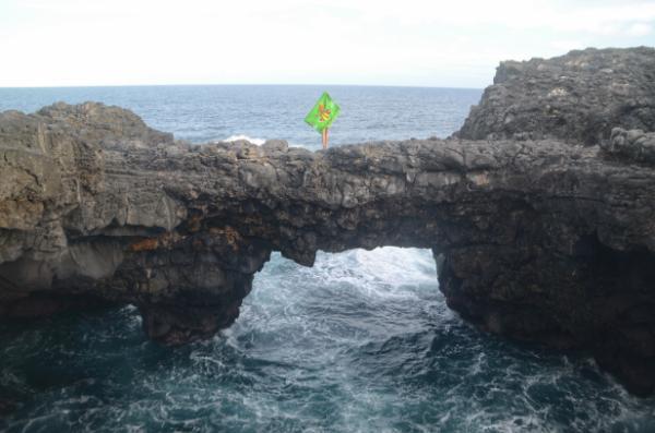 girl with green fabric standing atop pont naturel rock in mauritius