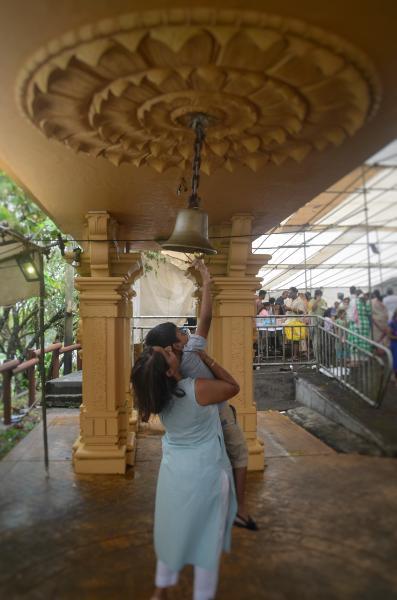 woman helping boy to reach the bell at hindu festival in mauritius