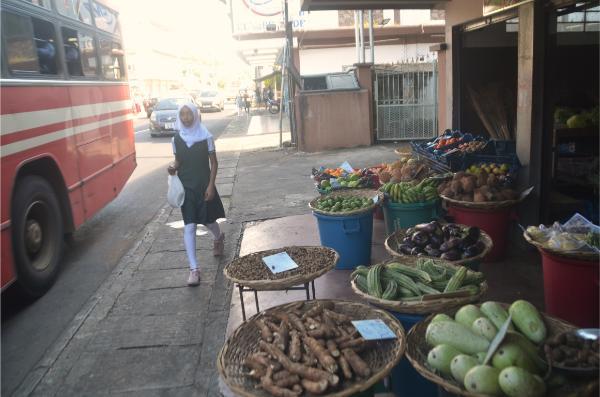 muslim girl walking by vegetable shop on the main road of Triolet, mauritius