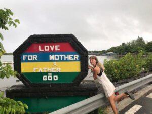 girl posing beside a positive message sign in mahebourg, mauritius