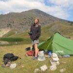 girl posing beside tent while camping by the dragon lake below the summit of mount smolikas in greece