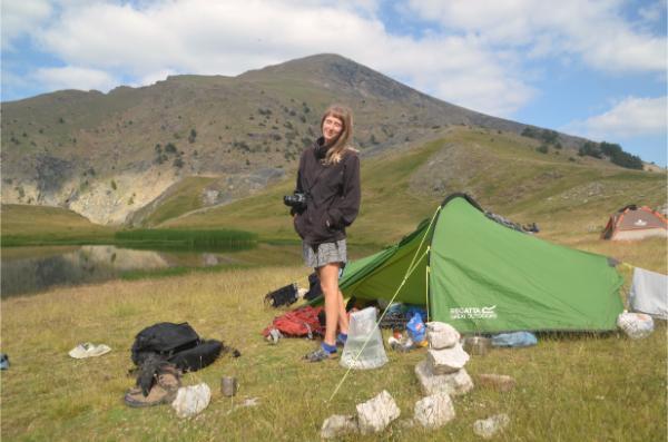 girl posing beside tent while camping by the dragon lake below the summit of mount smolikas in greece