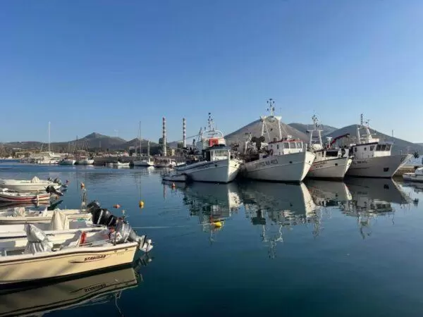 photo of fishing boats with a factory on the background taken at the port of aliveri on euboea island, greece